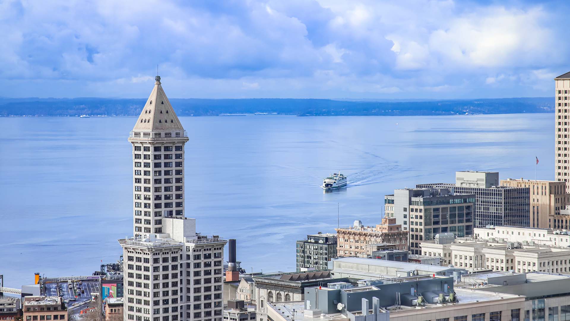 Seattle skyline with Smith Tower in front of boats sailing on Elliot Bay.