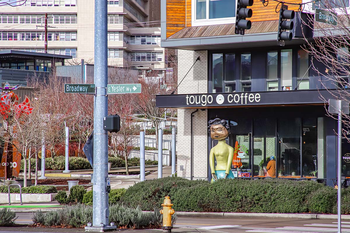 Tougo Coffee with human sculpture and landscaping at corner of Broadway and Yesler way in Seattle.